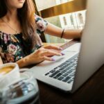 Woman Wearings Coop Neck Floral Top Using Her Apple Brand Macbook